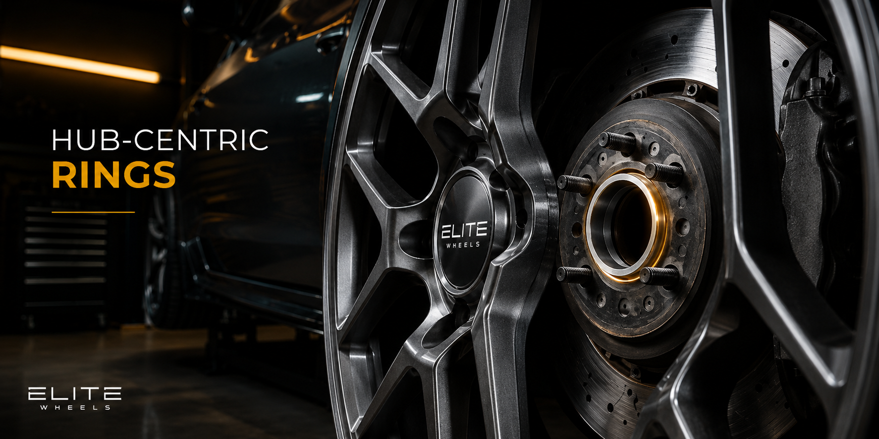Close-up of aftermarket wheel hub, hub-centric ring, and wheel installation hardware in a dramatic Elite Wheels garage scene